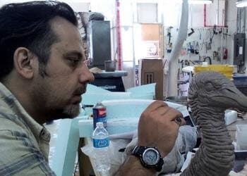 Nikos Dresios painting a creature head at the bench